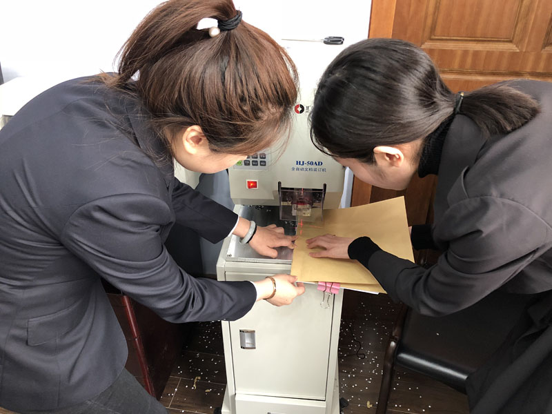 圖二：記者（左一）在工作人員的幫助下裝訂了一本案卷。