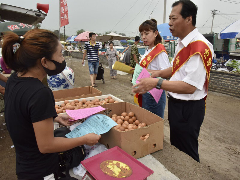 1錦州市委政法委政治部主任、市掃黑辦宣傳組組長李偉(右一)走進(jìn)集市進(jìn)行普法宣傳