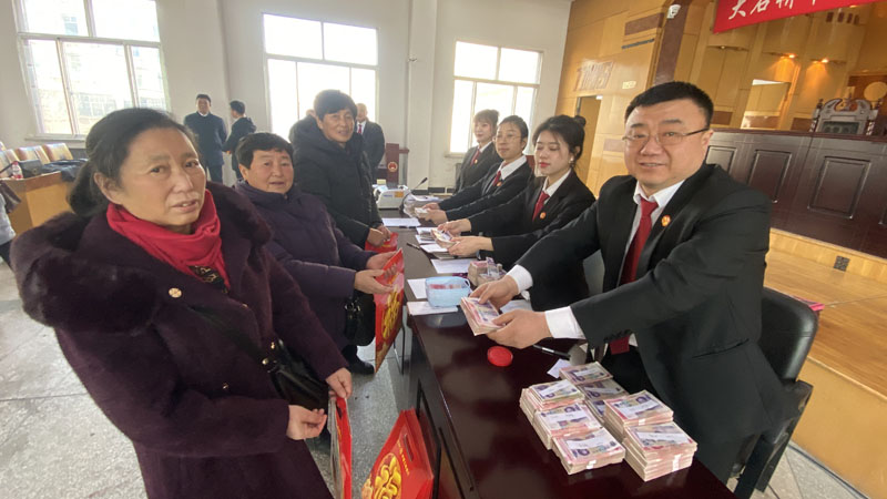 徐斌（左二）領(lǐng)取工資款；右一是大石橋市人民法院執(zhí)行員王敬偉