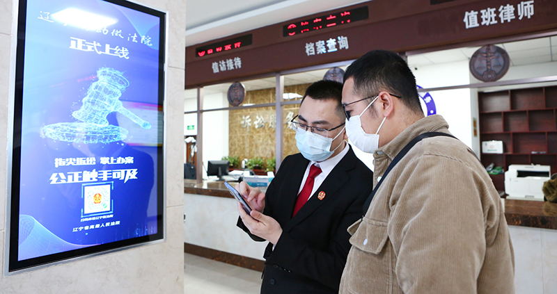 付承志（左）正在教記者使用“遼寧微法院”系統(tǒng)