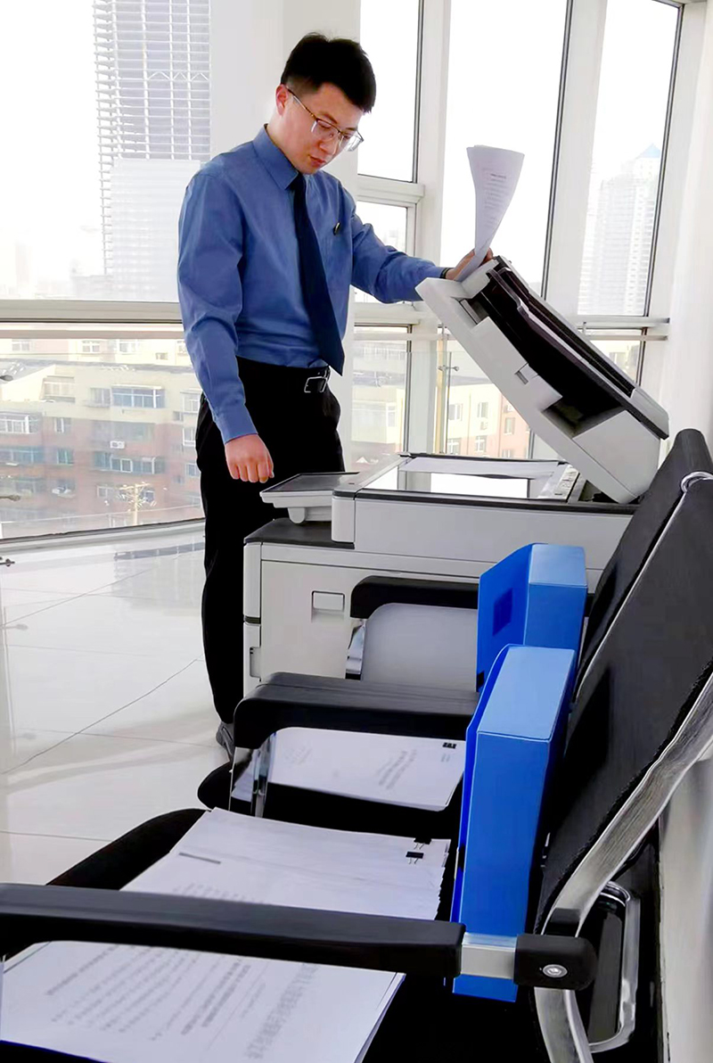 圖為：鄒士軍為各處室領(lǐng)導(dǎo)復(fù)印待傳閱文件