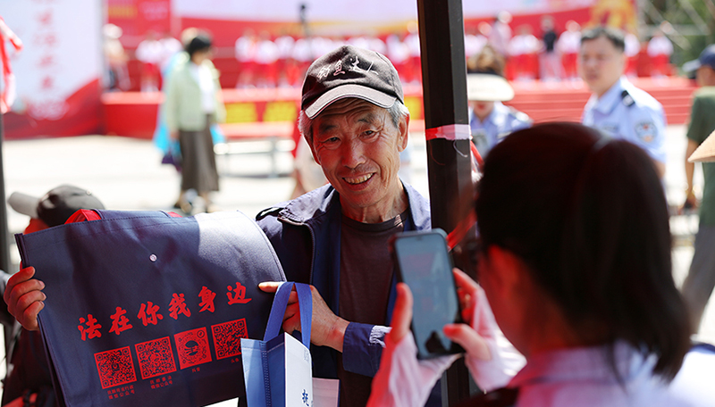 頭題圖，法治文藝節(jié)目展演活動(dòng)現(xiàn)場(chǎng)，司法局工作人員發(fā)放原創(chuàng)普法購物袋。