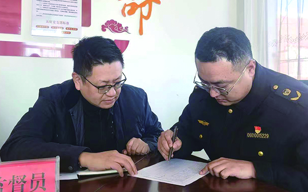 監(jiān)督員王雨飛（左）現(xiàn)場(chǎng)監(jiān)督執(zhí)法隊(duì)員于寧（右）填寫《月度自查清單》