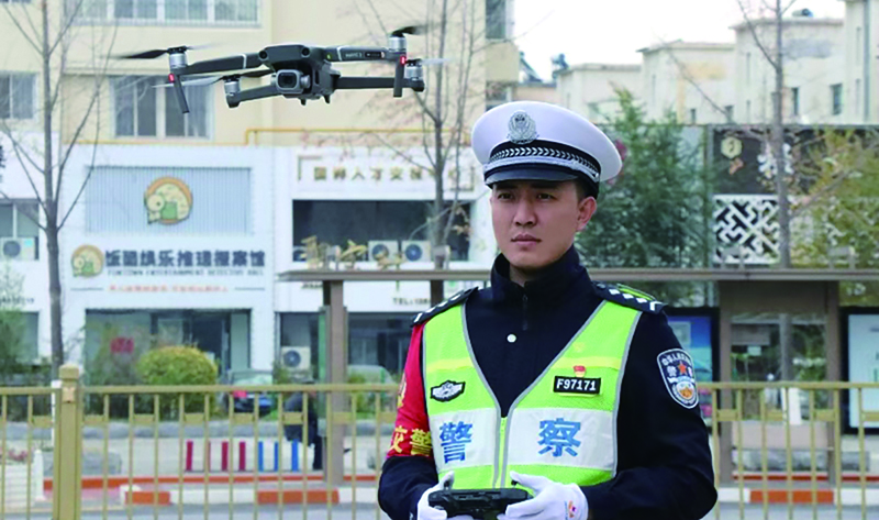 頭題圖，交警在執(zhí)勤工作中準備使用“無人機”監(jiān)控車流量。